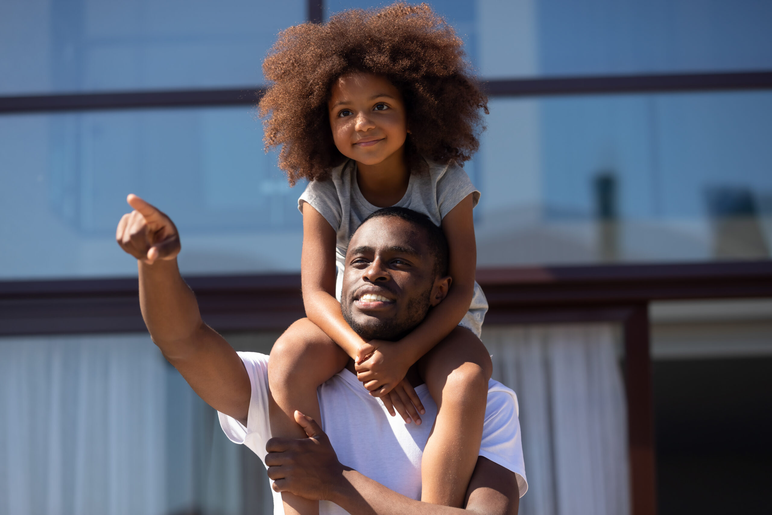 Dad-holding-young-daughter-on-shoulders-outdoors-scaled